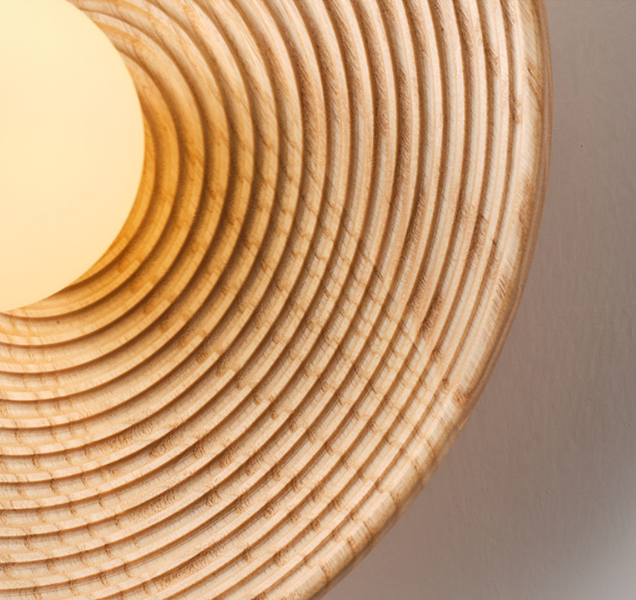 Detailed image of the smooth, light oak wood finish on a round flush wall sconce, minimalist design detail"