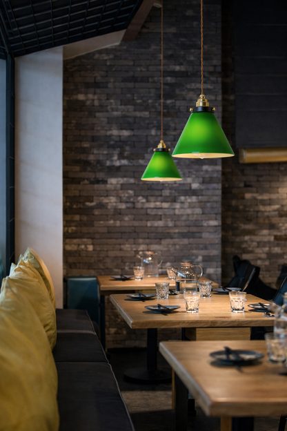 Modern cone  shape green glass pendant light hanging above a minimalist cafe table.