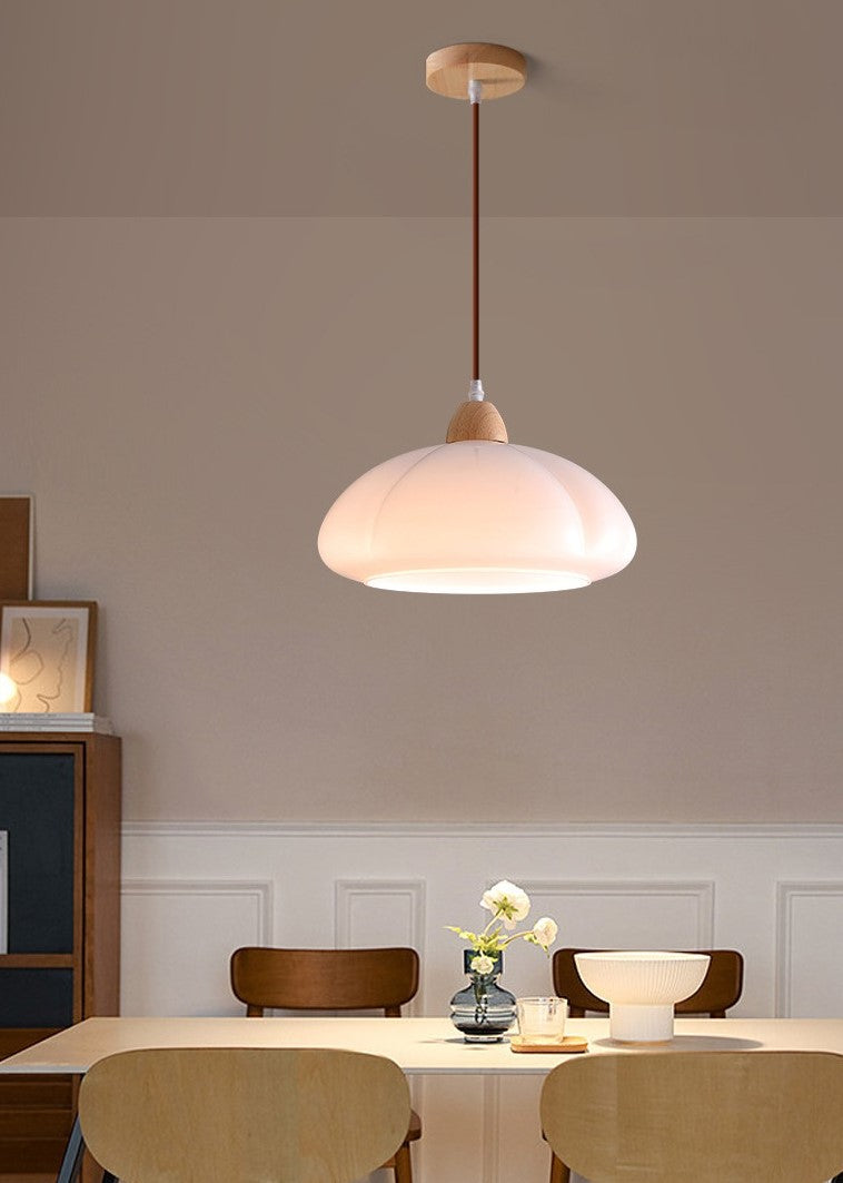 Organic-shaped white pendant light suspended low over a modern dining table for focused task lighting
