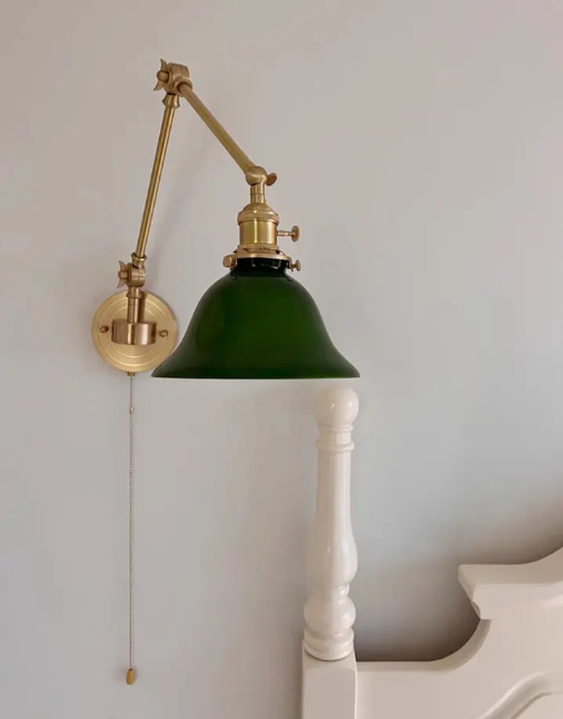 Vintage style brass wall sconce featuring a green glass banker lampshade and convenient pull chain switch