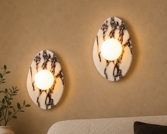 Two irregular oval marble wall sconces mounted on wall, natural stone design with frosted glass globe, Mashal designs lighting