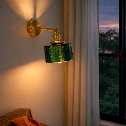 A beautiful wall sconce featuring a textured, emerald green glass shade mounted on a metal fixture; designed for hardwired installation